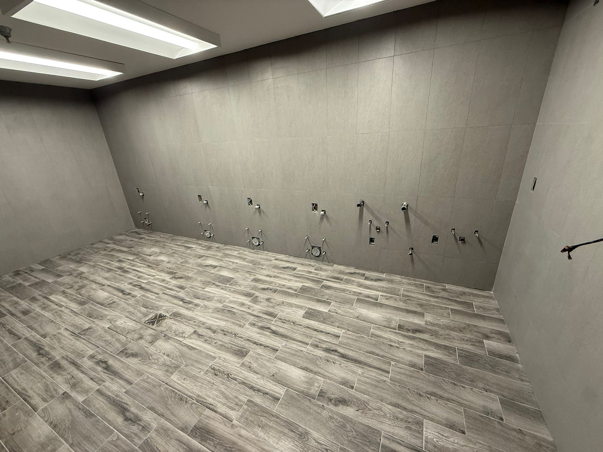 Kitchen wall and floor tile installation with white cabinets and gray floor tile